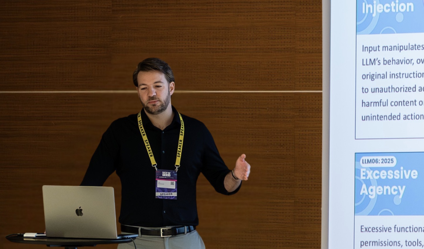 Jan Broniowski speaking at a conference, an OWASP Top 10 for LLM Applications slide on screen